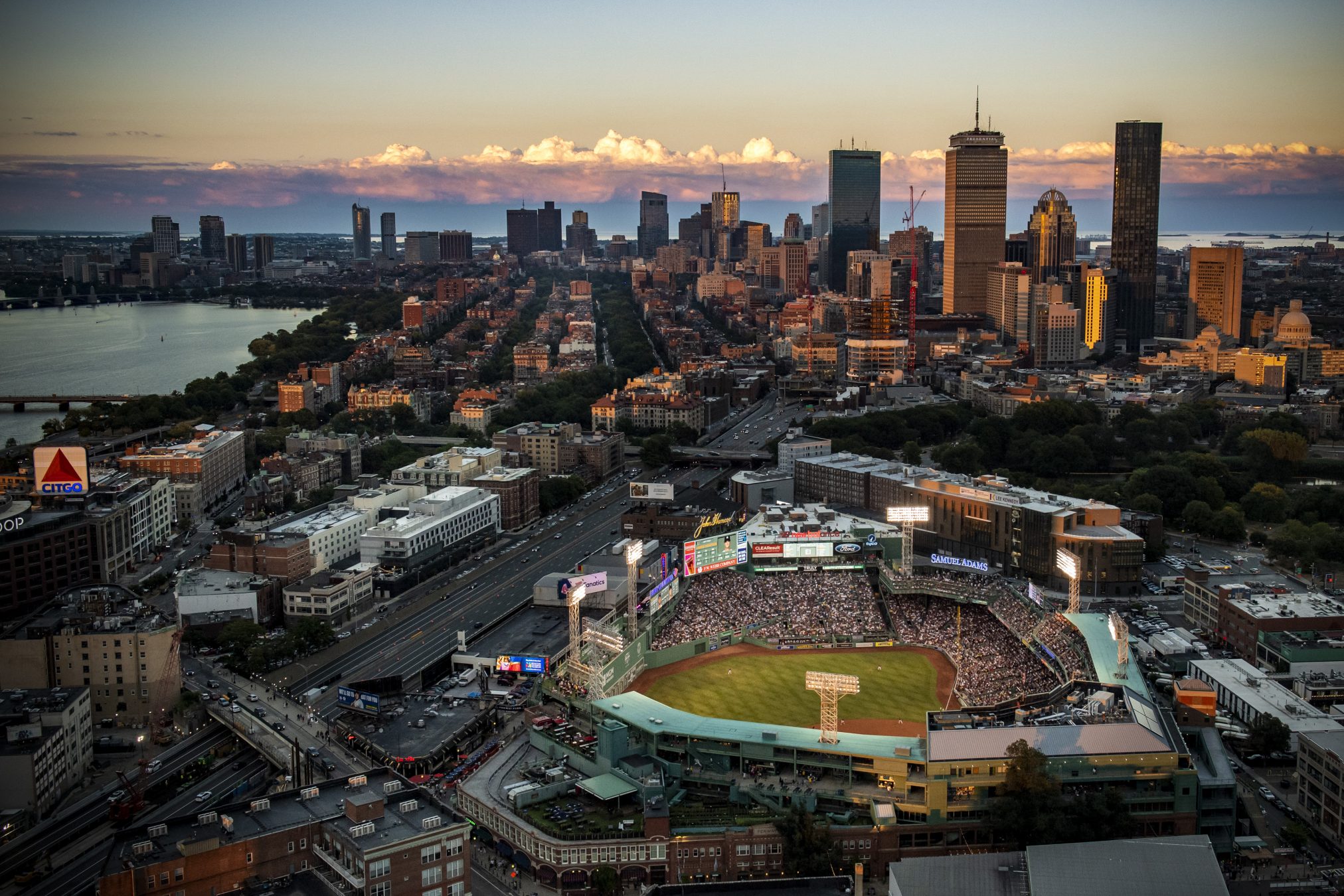 Aerial view of Fenway Park at dusk with the Back Bay and downtown Boston skyline behind it